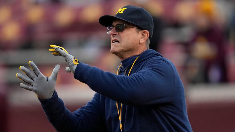 FILE - Michigan head coach Jim Harbaugh looks to catch a pass before an NCAA college football...